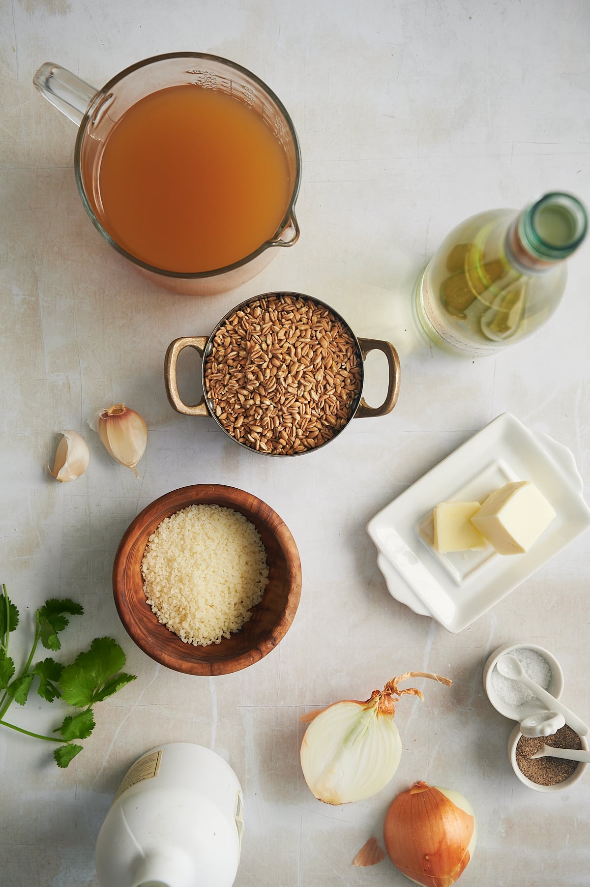 bowls of ingredient for farro and parmesan risotto including farro, butter, wine and parmesan