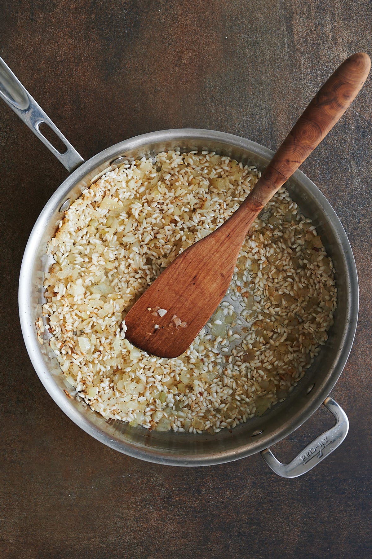 Adding vinegar to toasted rice in skillet for risotto