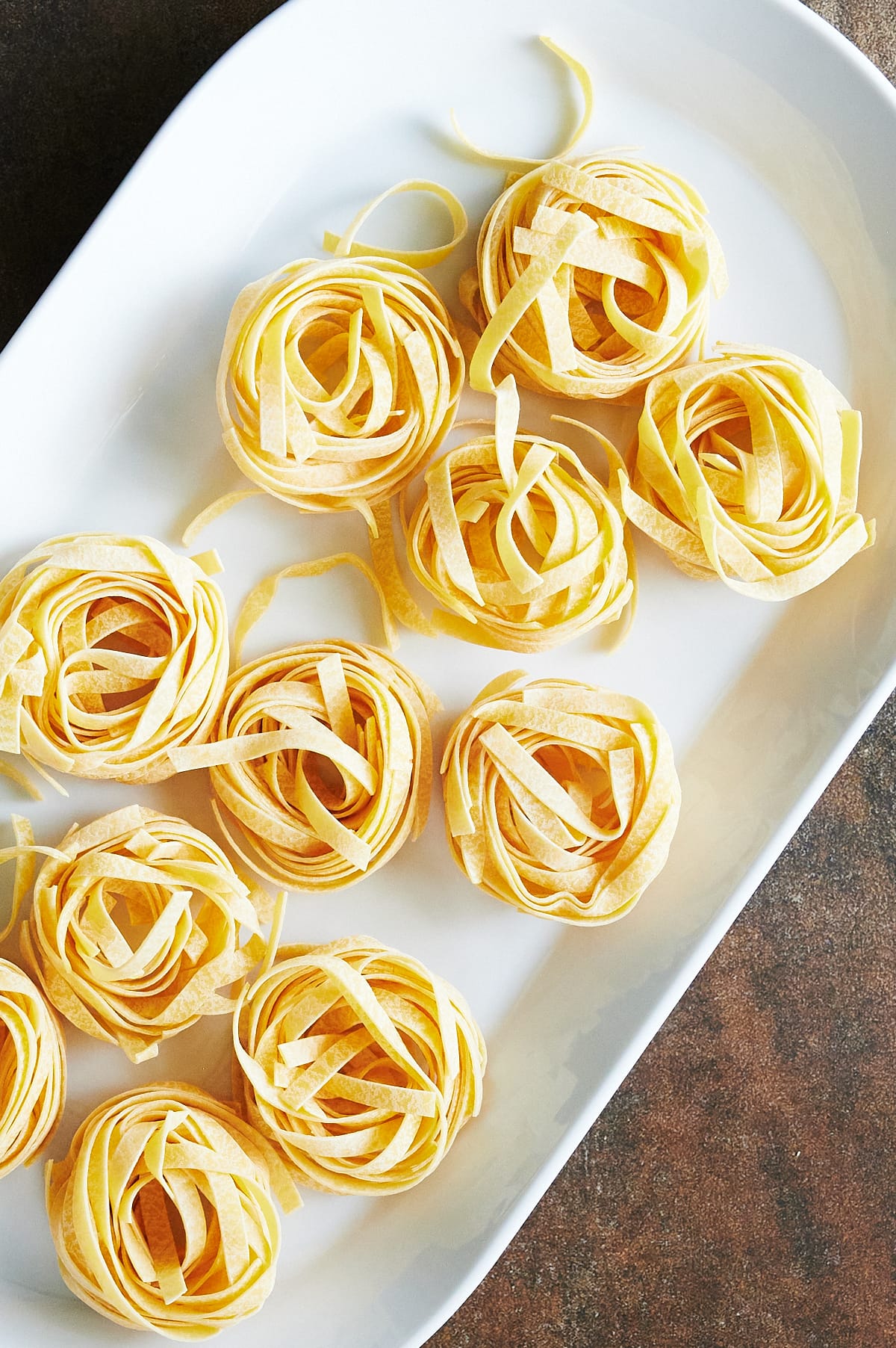white tray of nests of tagliatelle ready for Bolognese.