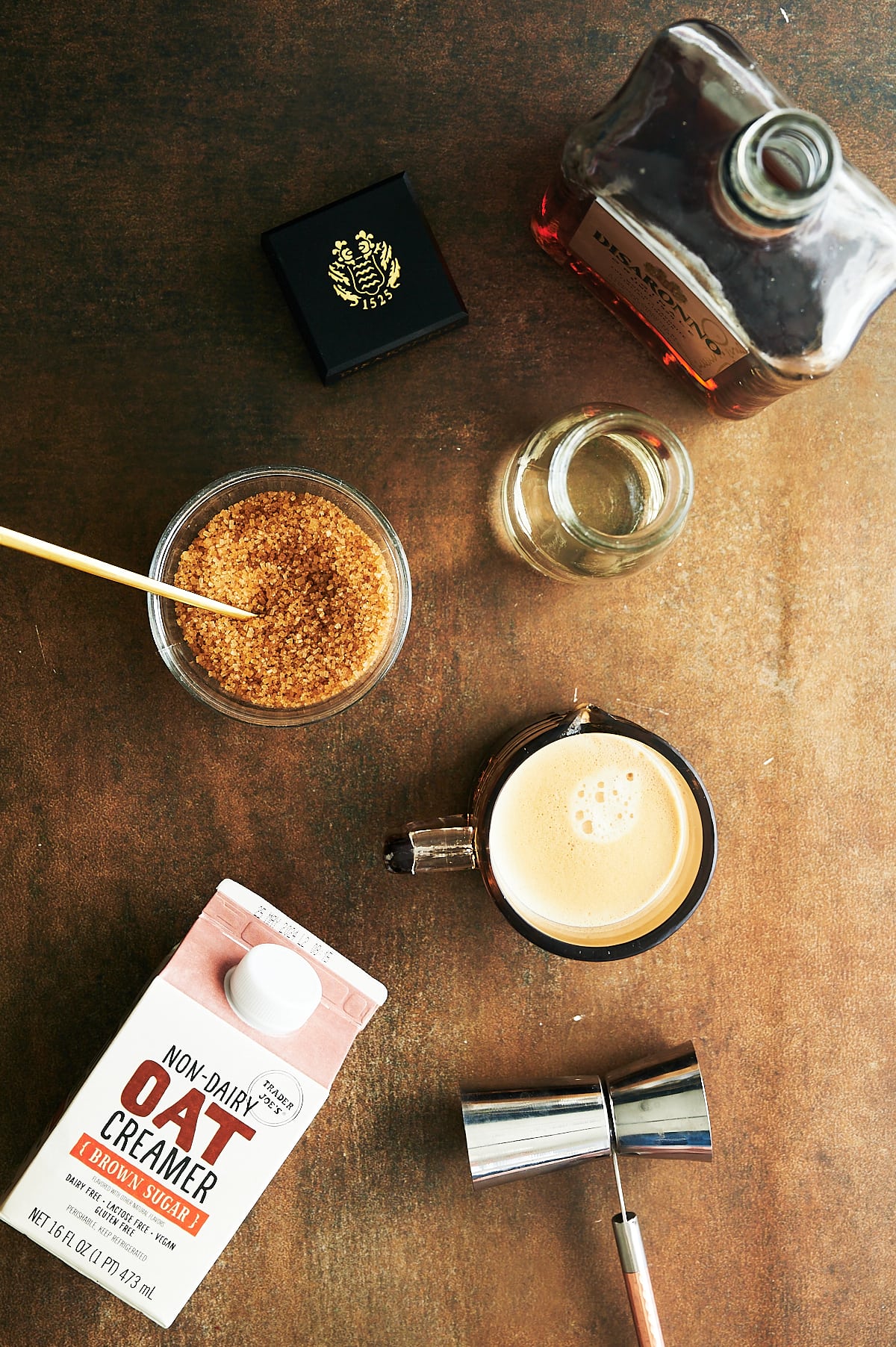 Ingredients for amaretto coffee with demerara sugar, oat milk creamer and coffee.