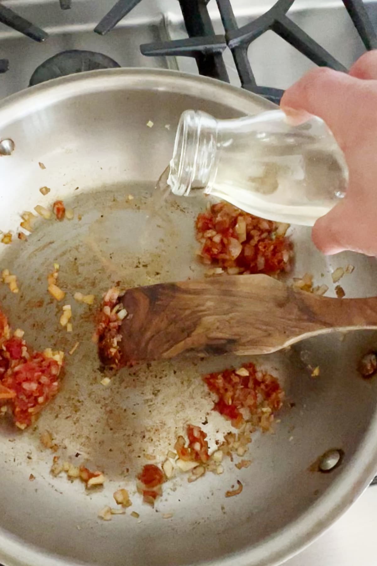 White wine being added to pan of caramelized tomato paste and onions.