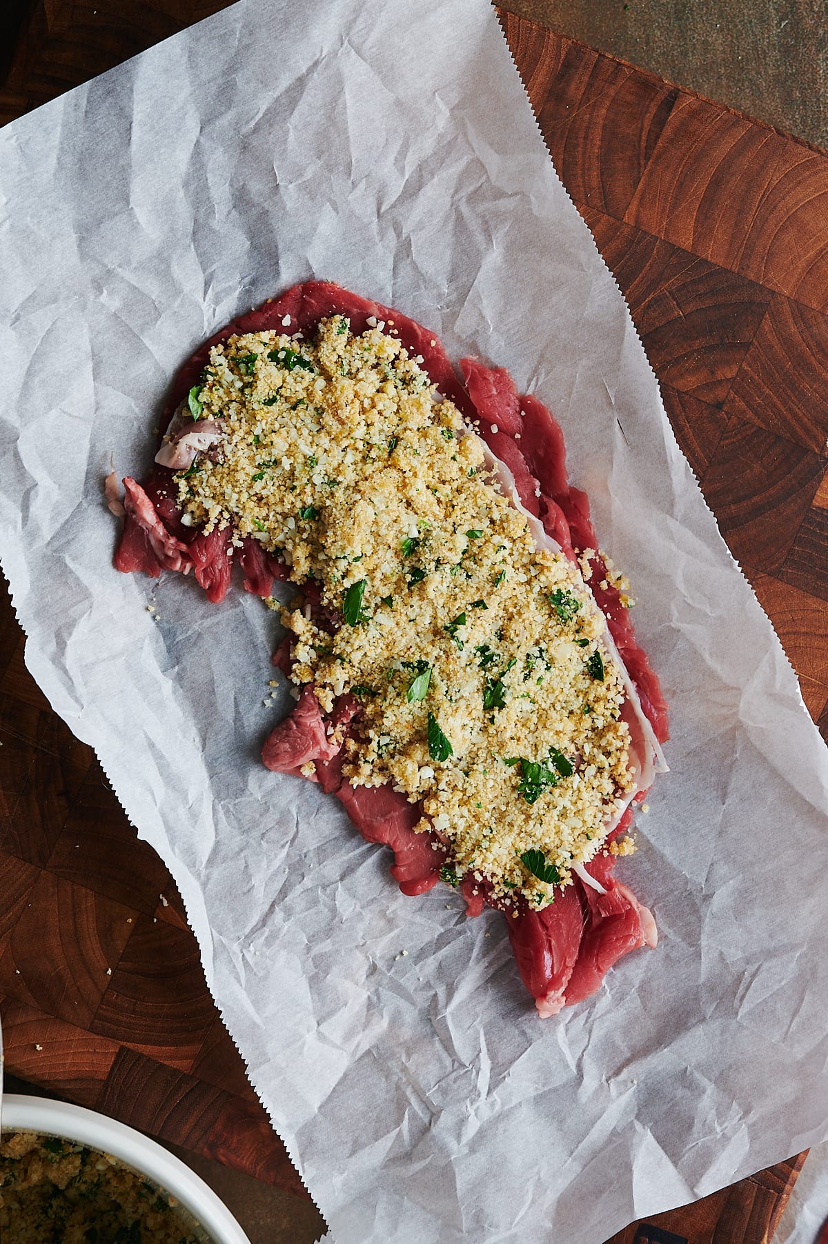 breadcrumb filling on open piece of raw steak for braciole.