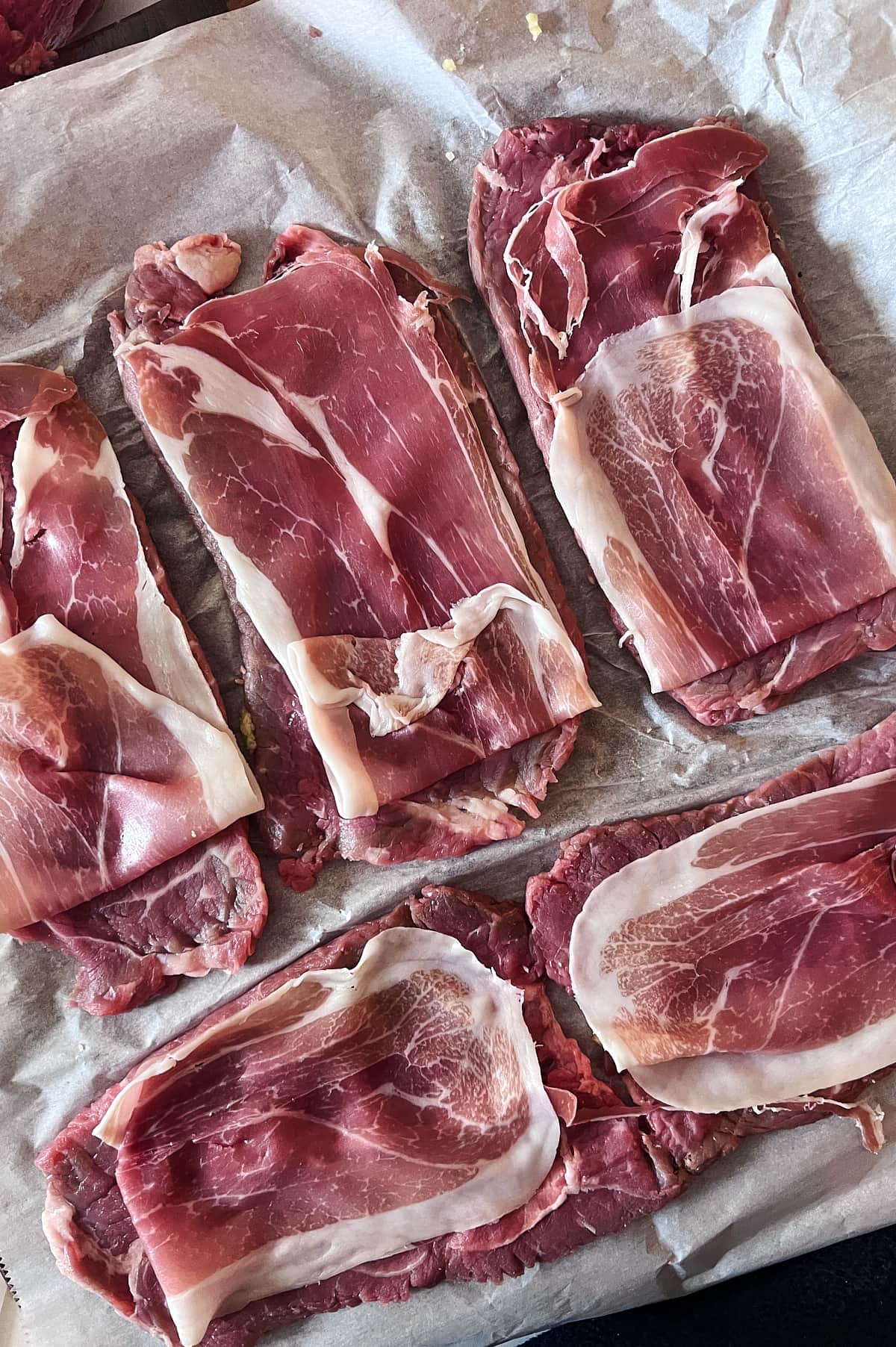 beef for braciole with prosciutto slices placed on top.