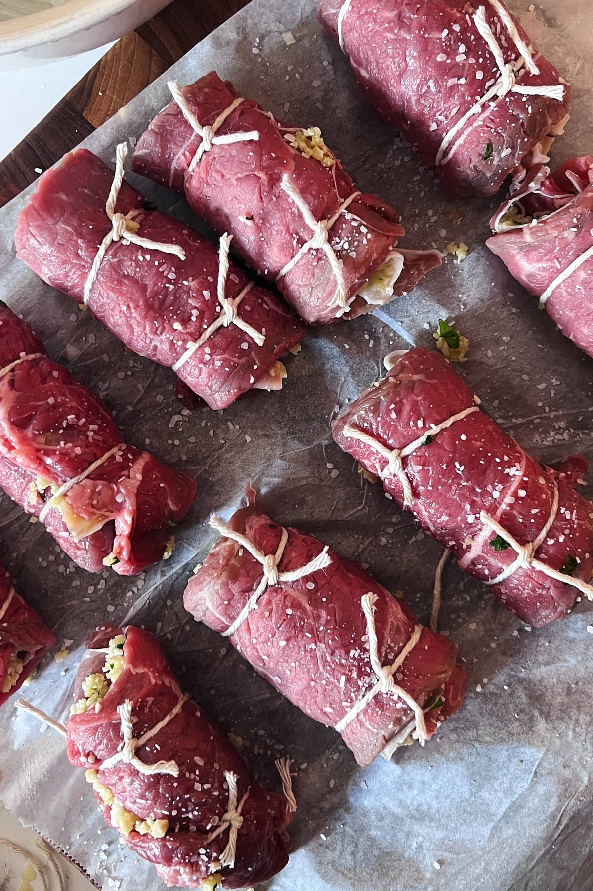tied rolls of beef braciole on parchment before being cooked.