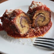 Finished white dish of beef braciole with red sauce.
