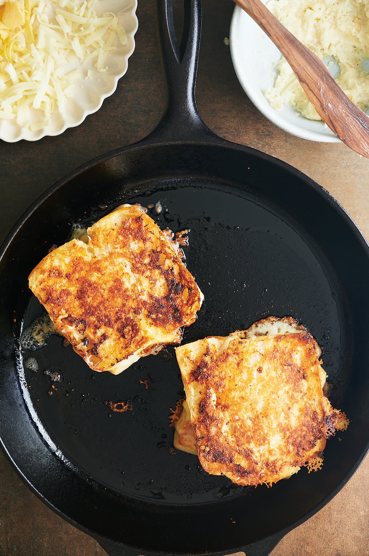 Cast iron skillet with two garlic bread grilled cheese sandwiches.