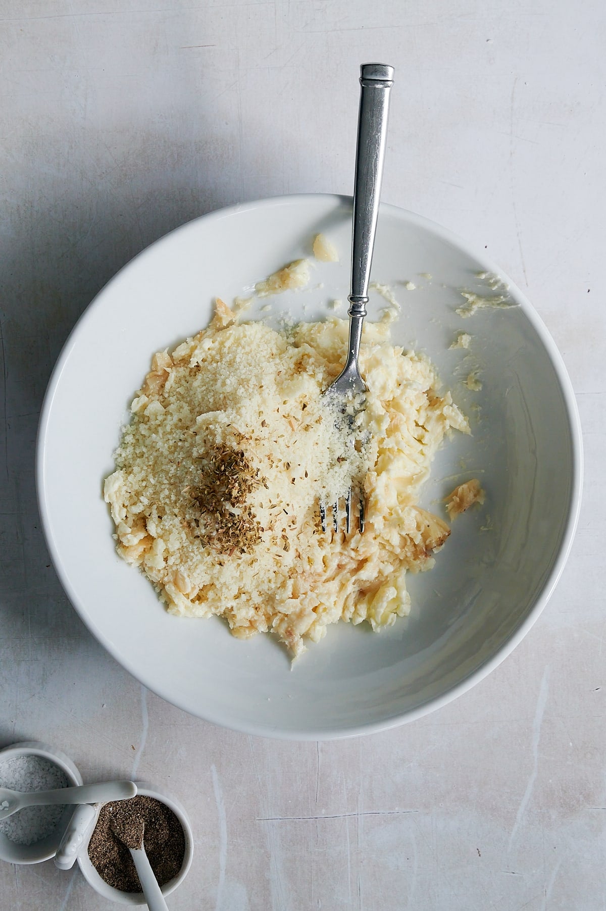 Parmesan and pepper in garlic butter in white bowl with fork.