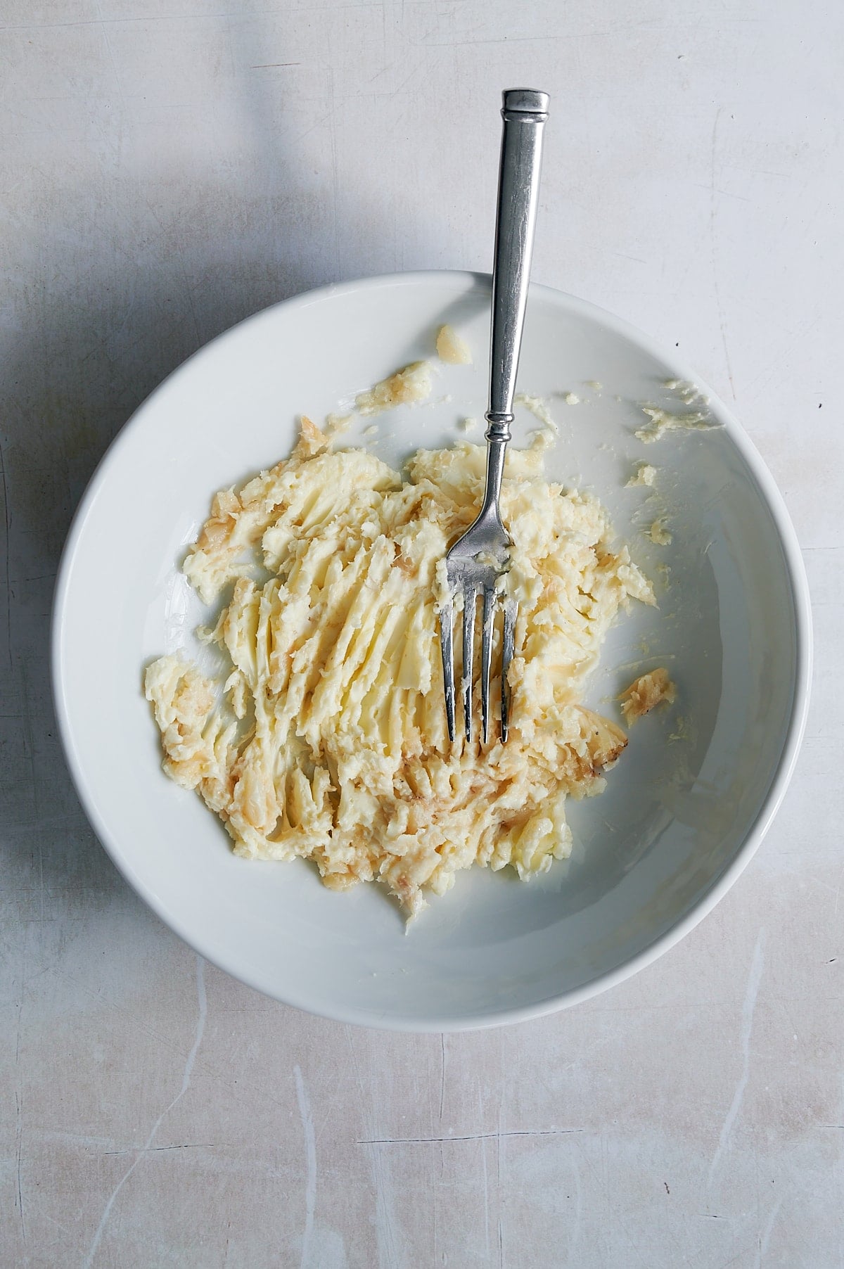 Mixing roasted garlic into butter for garlic bread grilled cheese.