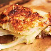 Close up of toasted grilled cheese sandwiches with a cheese pull on a wooden board.