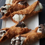 white tray with ricotta cannoli some with chocolate on them.