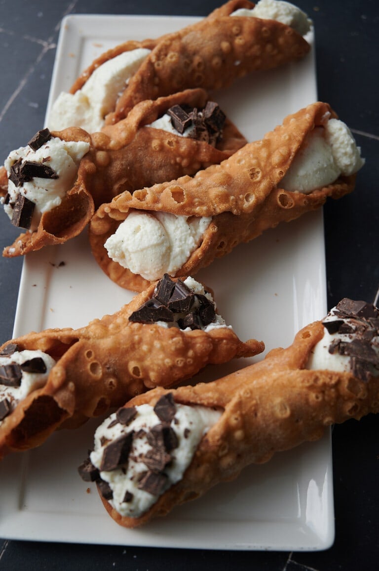 white tray with ricotta cannoli some with chocolate on them.