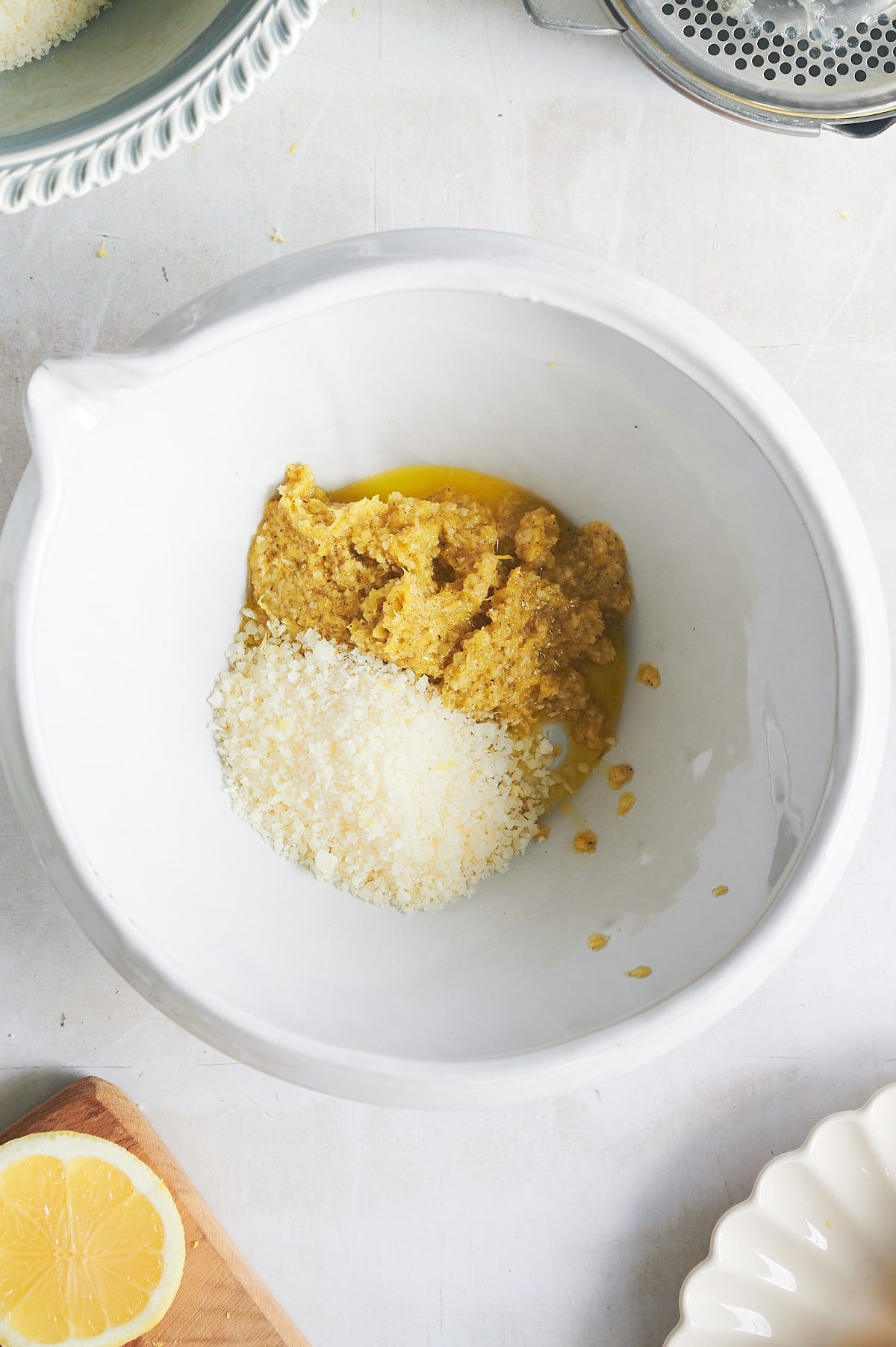 white bowl of grated parmesan being mixed into lemon pesto.