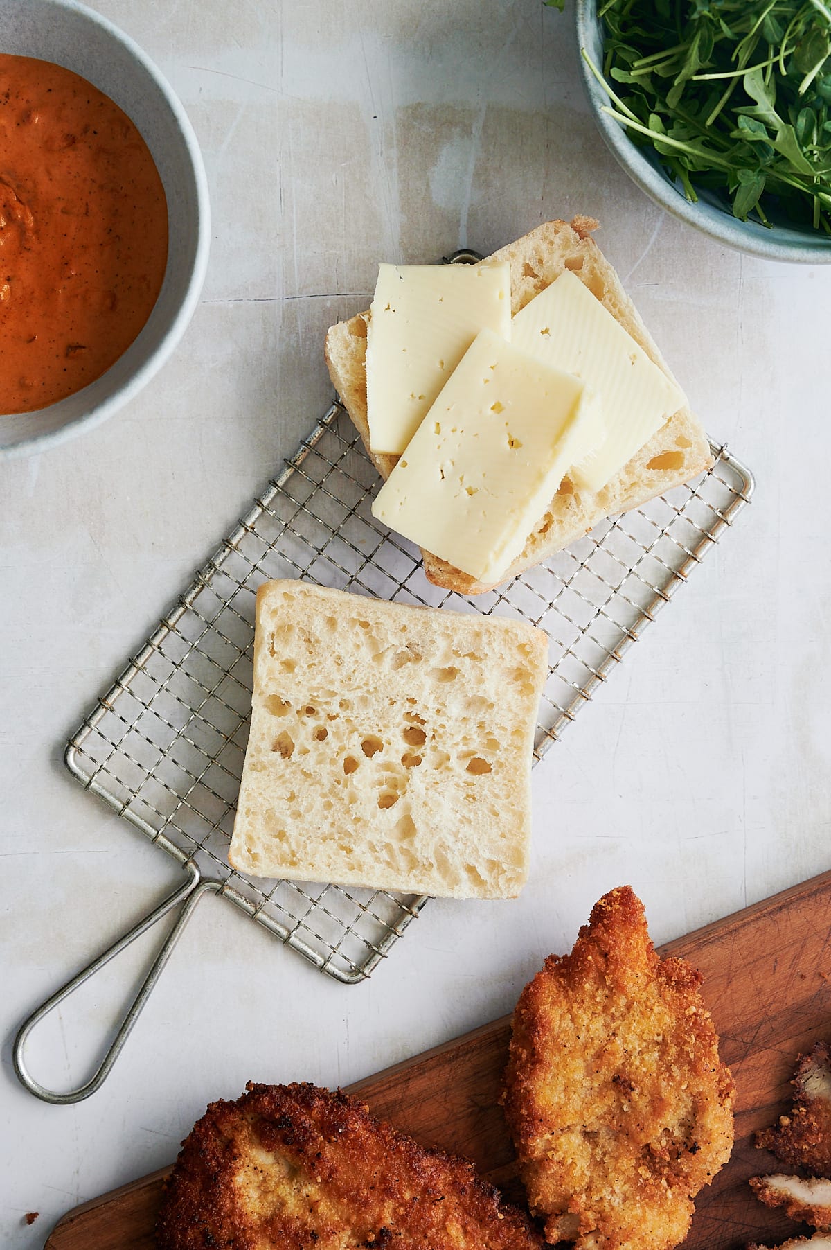 fontina cheese on ciabatta rolls on wire rack for chicken cutlet sandwiches.