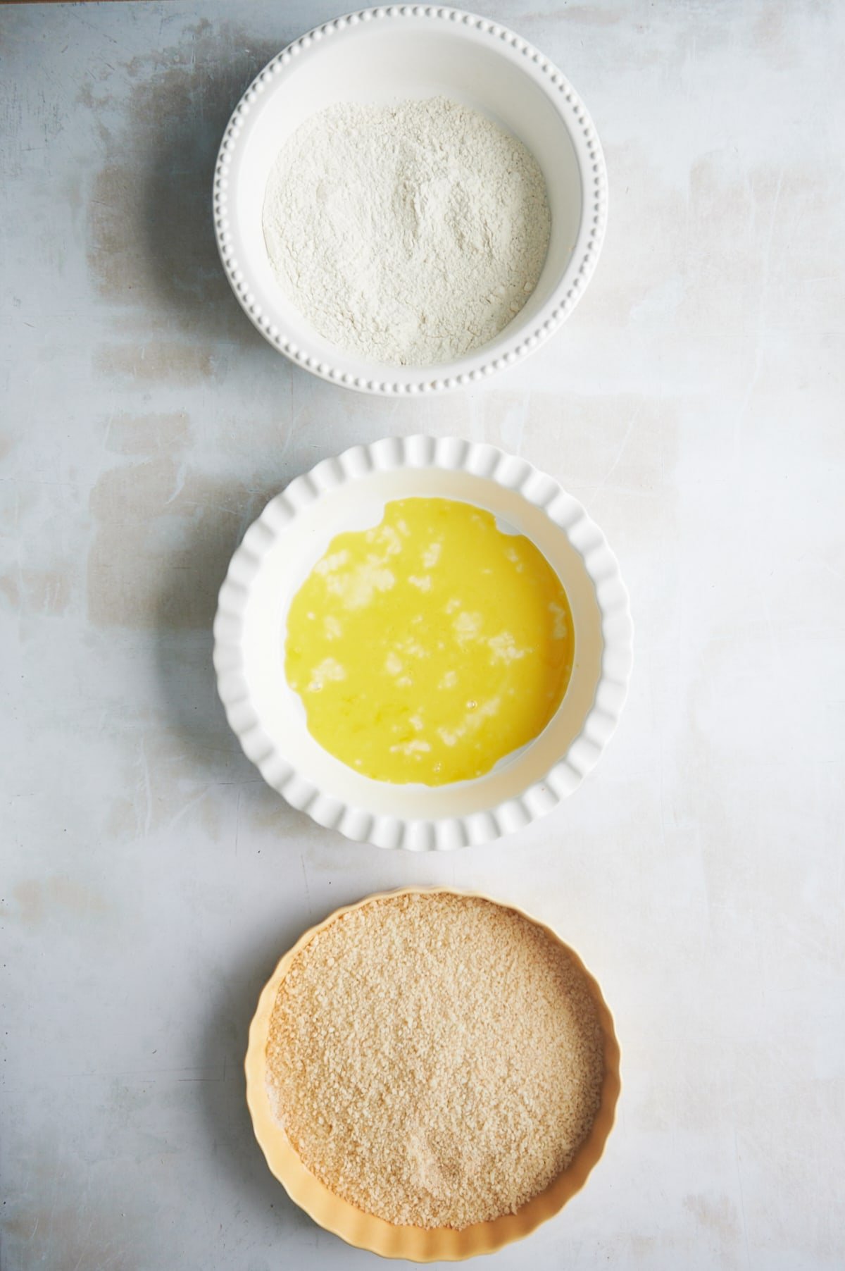 three pie plates with ingredients for breading station for chicken