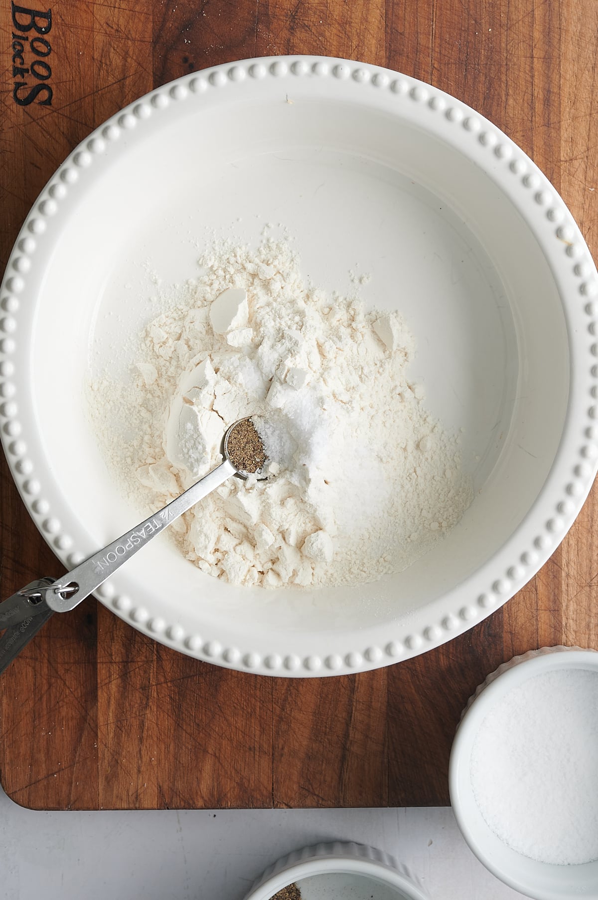 white pie plate with flour and seasoning for breading chicken.
