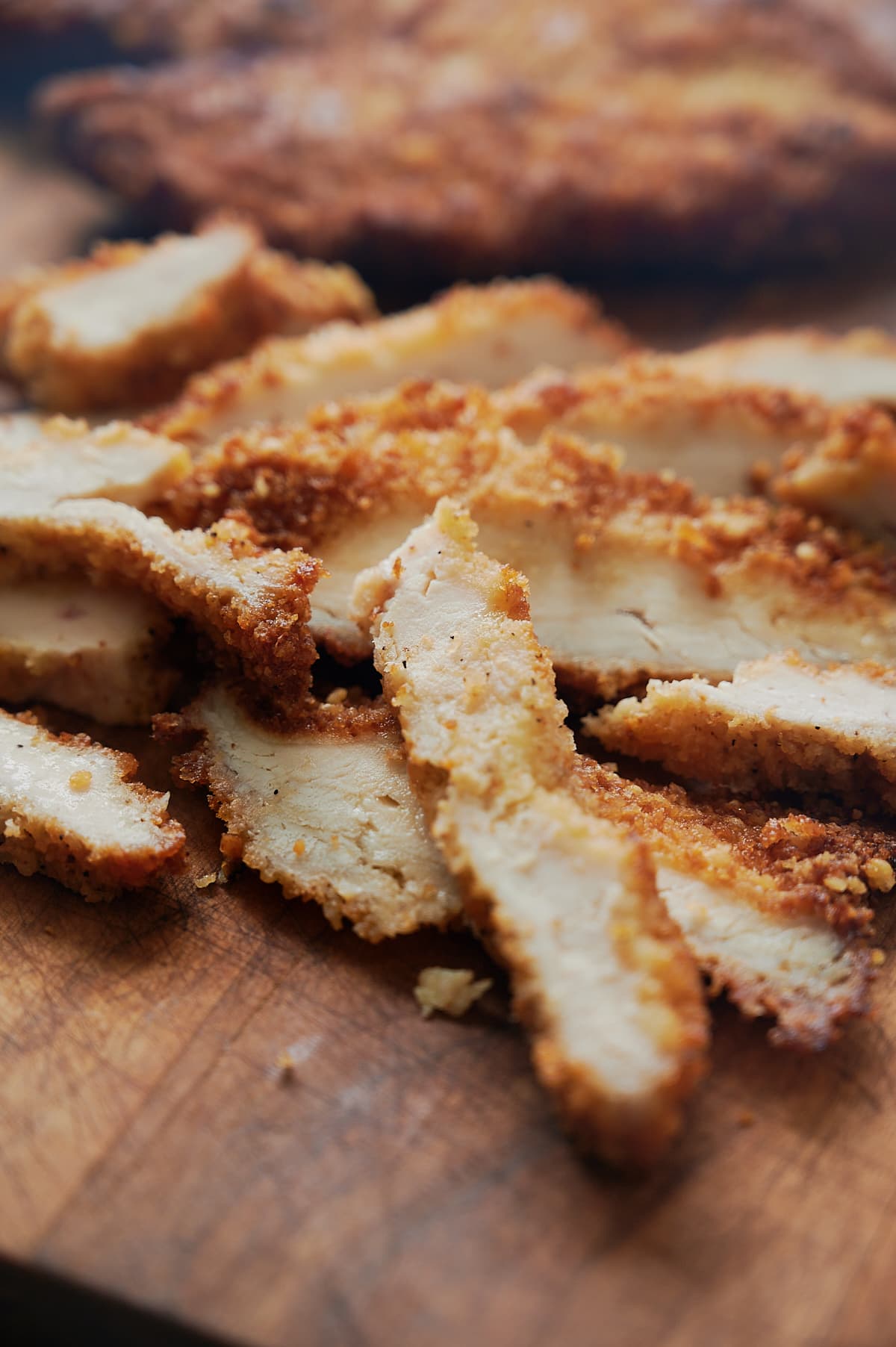 Sliced chicken cutlets on a wooden board ready to eat.