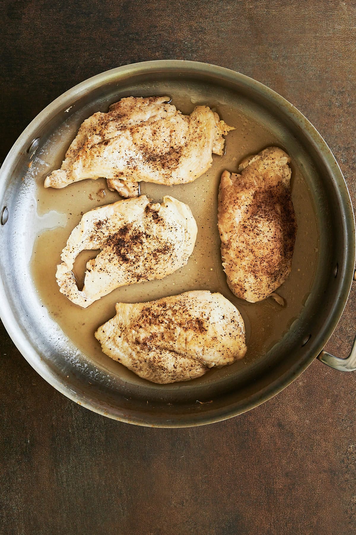 pan of chicken breasts cooked with broth.