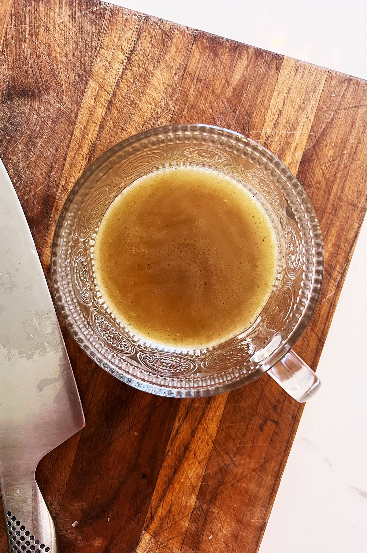wooden board with embossed cup holding chicken broth.