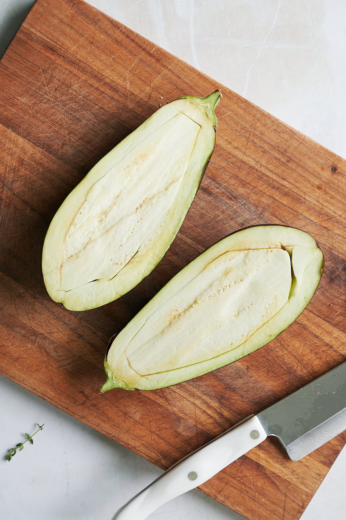 Scoring eggplant with a knife to scoop out flesh for stuffed eggplant.