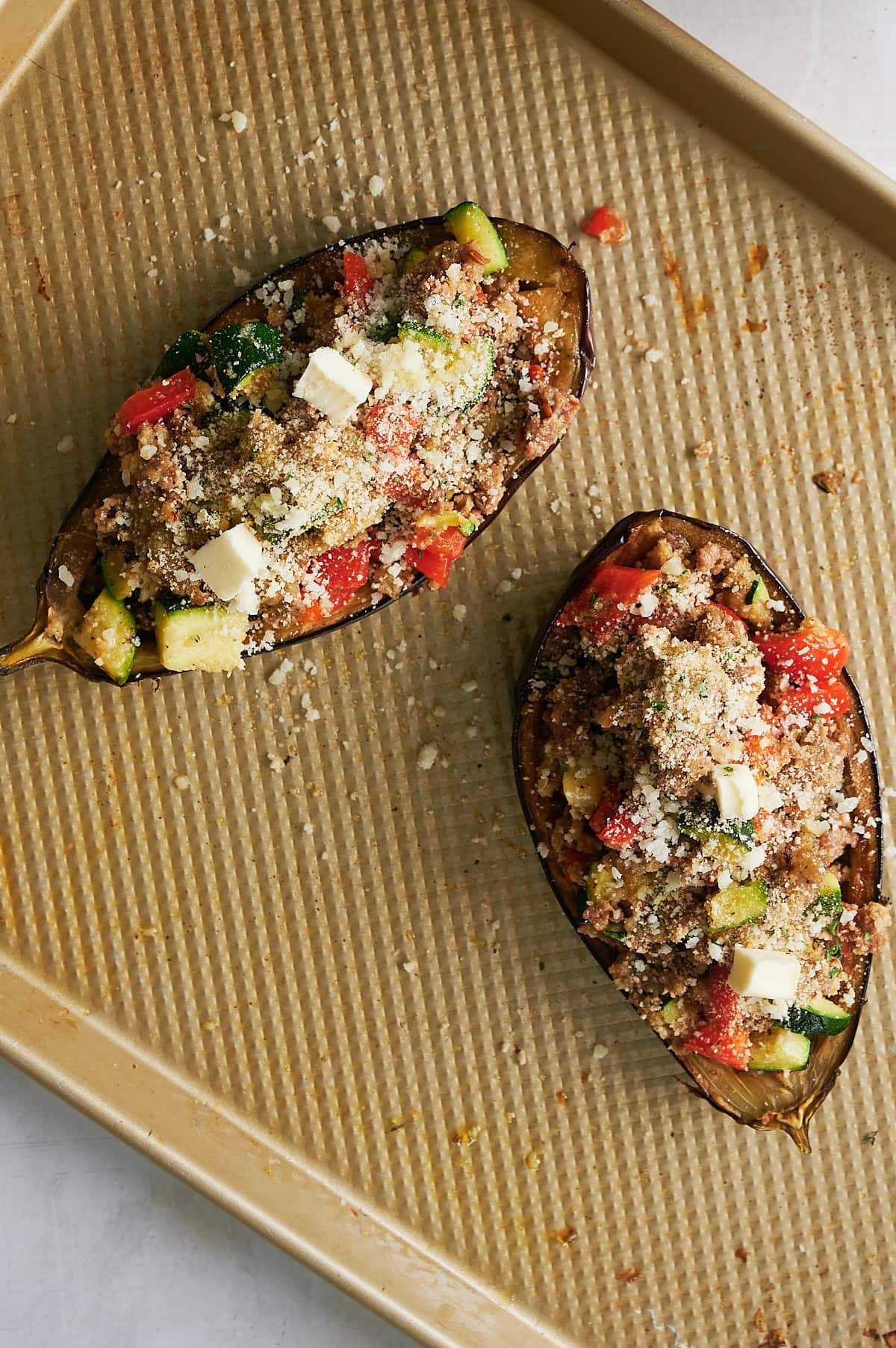 2 stuffed eggplant halves on a sheet pan ready to bake.