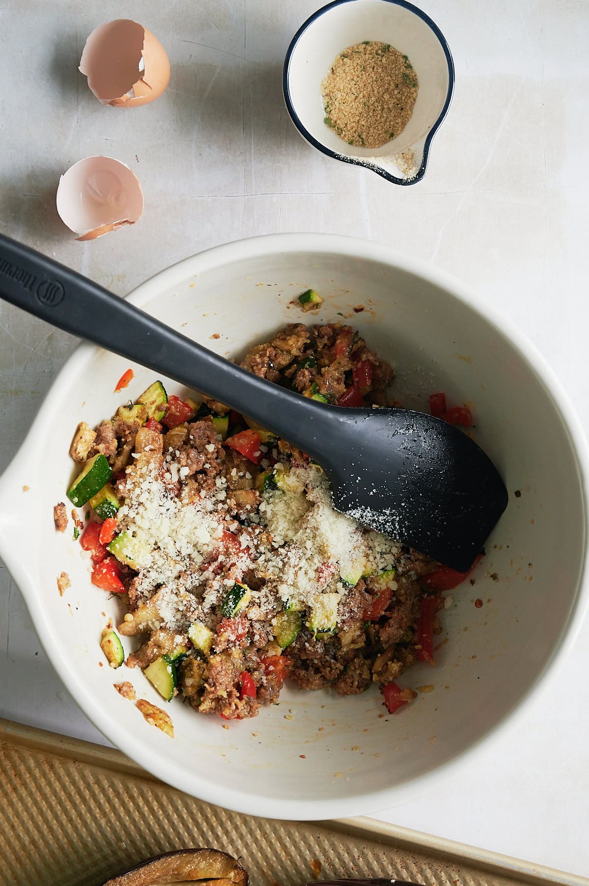 Mixing filling for stuffed eggplant with cheese and breadcrumbs.