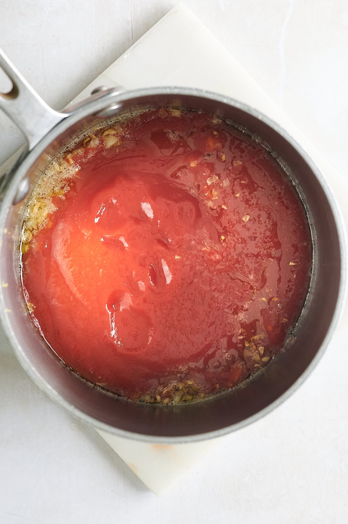 saucepan with marinara dipping sauce on marble slab.