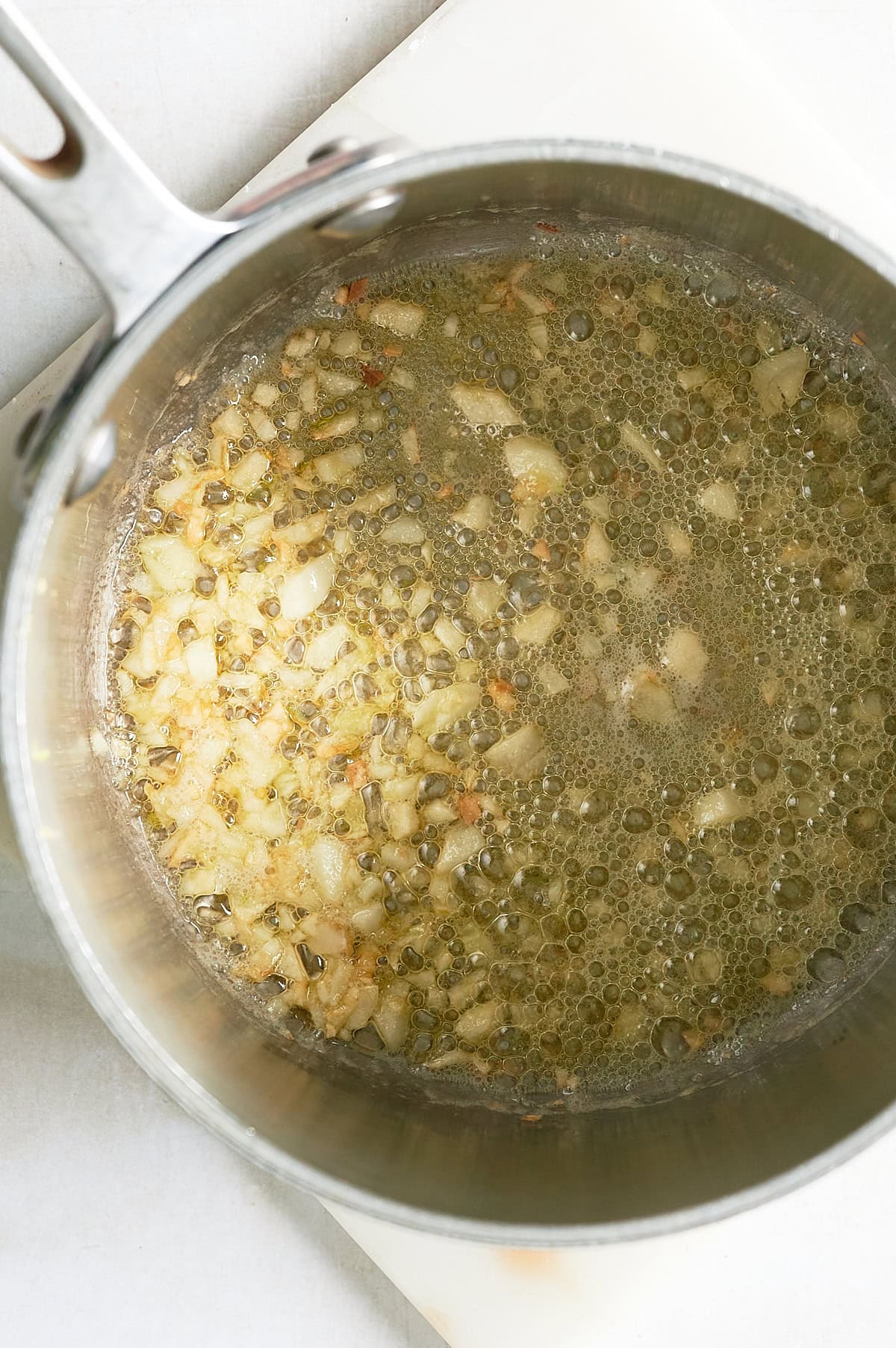 saucepan of olive oil and garlic onions sauteeing.