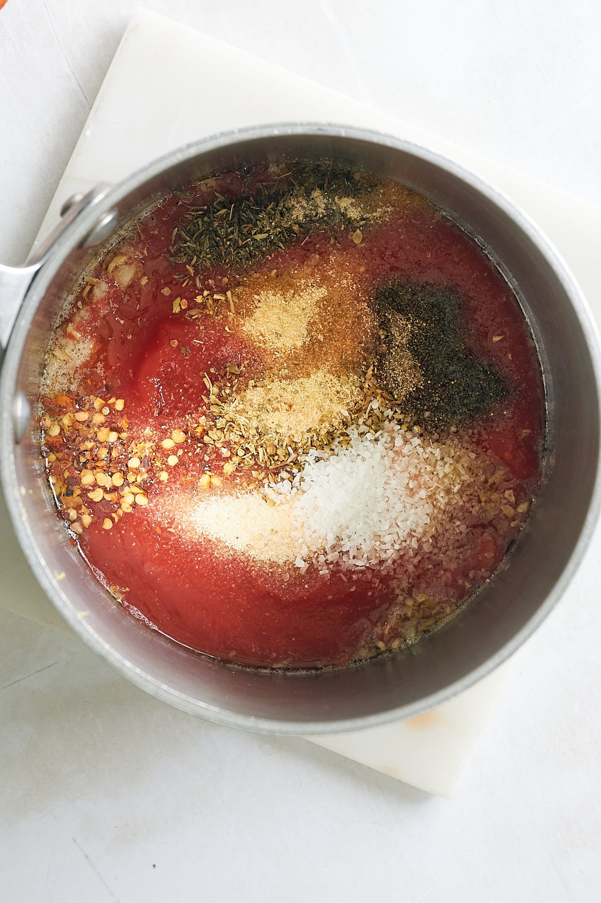 saucepan of marinara dipping sauce with seasoning on top.