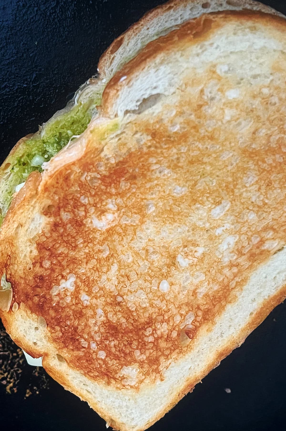 toasted pesto grilled cheese sandwich in a cast iron skillet.