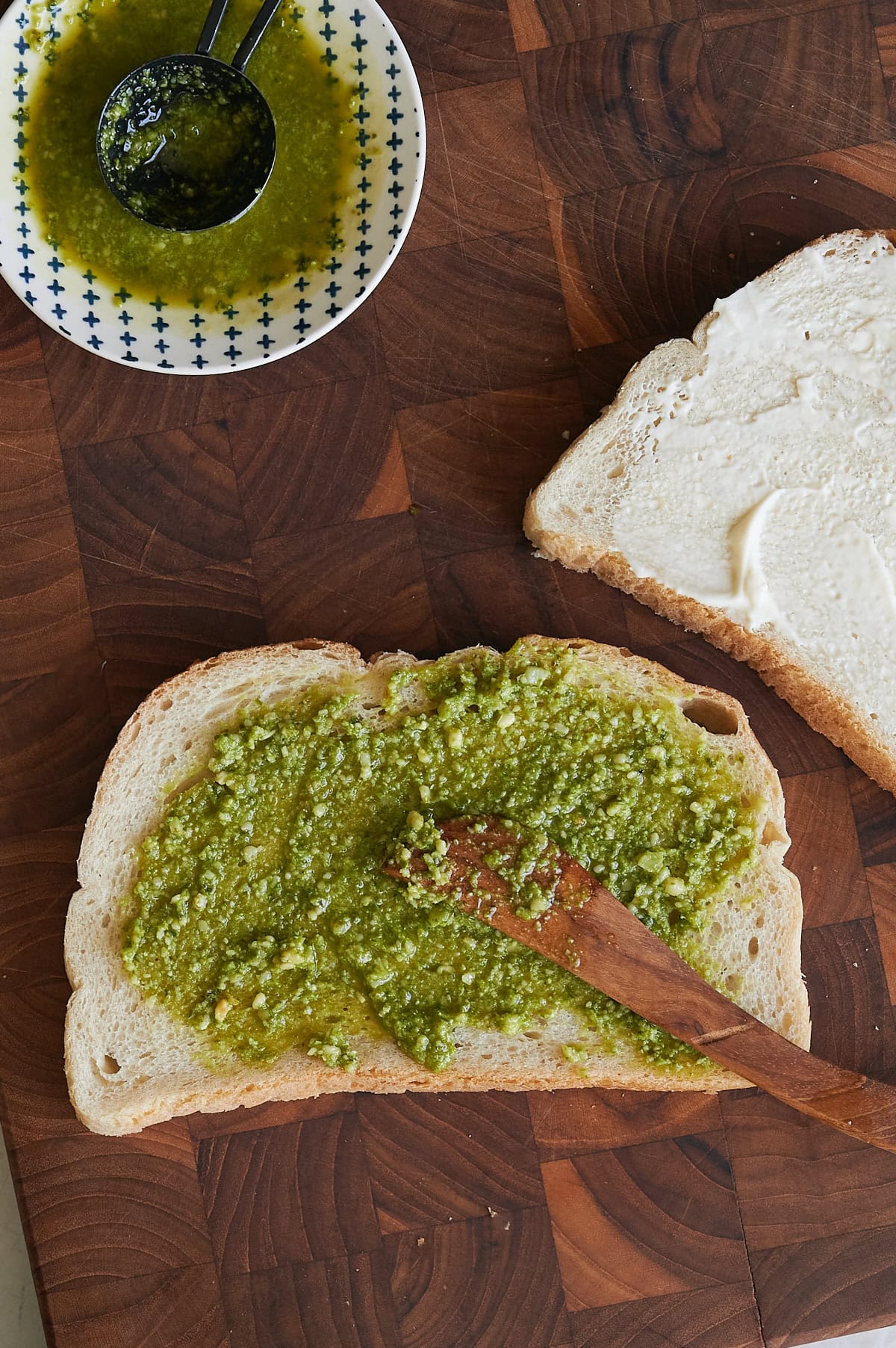 pesto being spread on bread for grilled cheese.