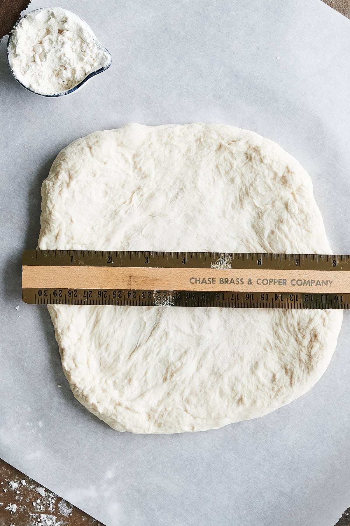 ruler measuring calzone dough on parchment.