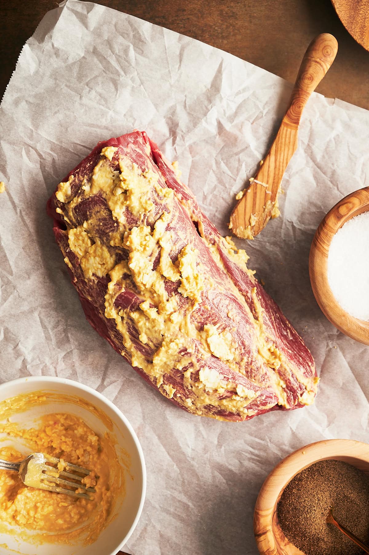 beef tenderloin prepped with butter and mustard on parchment paper.