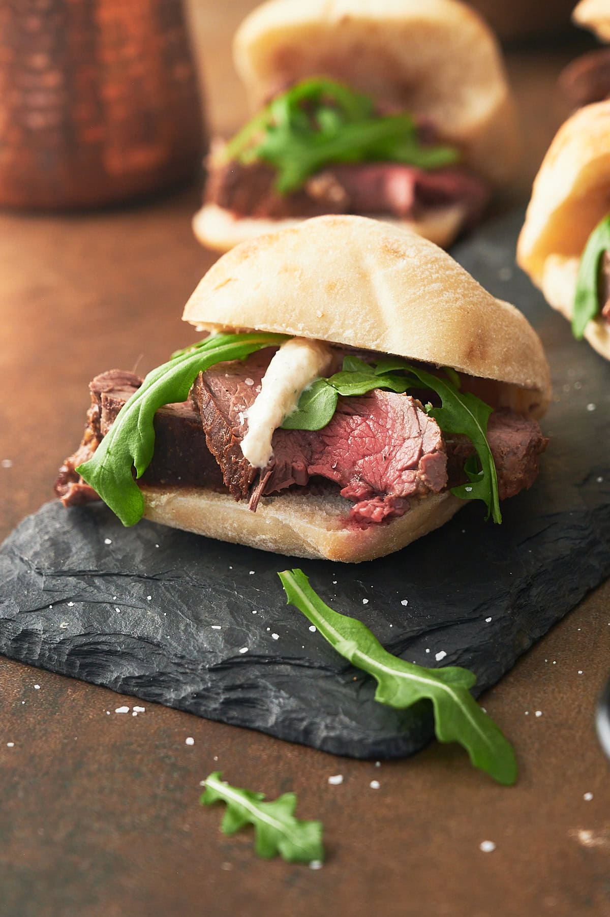 beef tenderloin slider sandwich with horseradish sauce on slate.