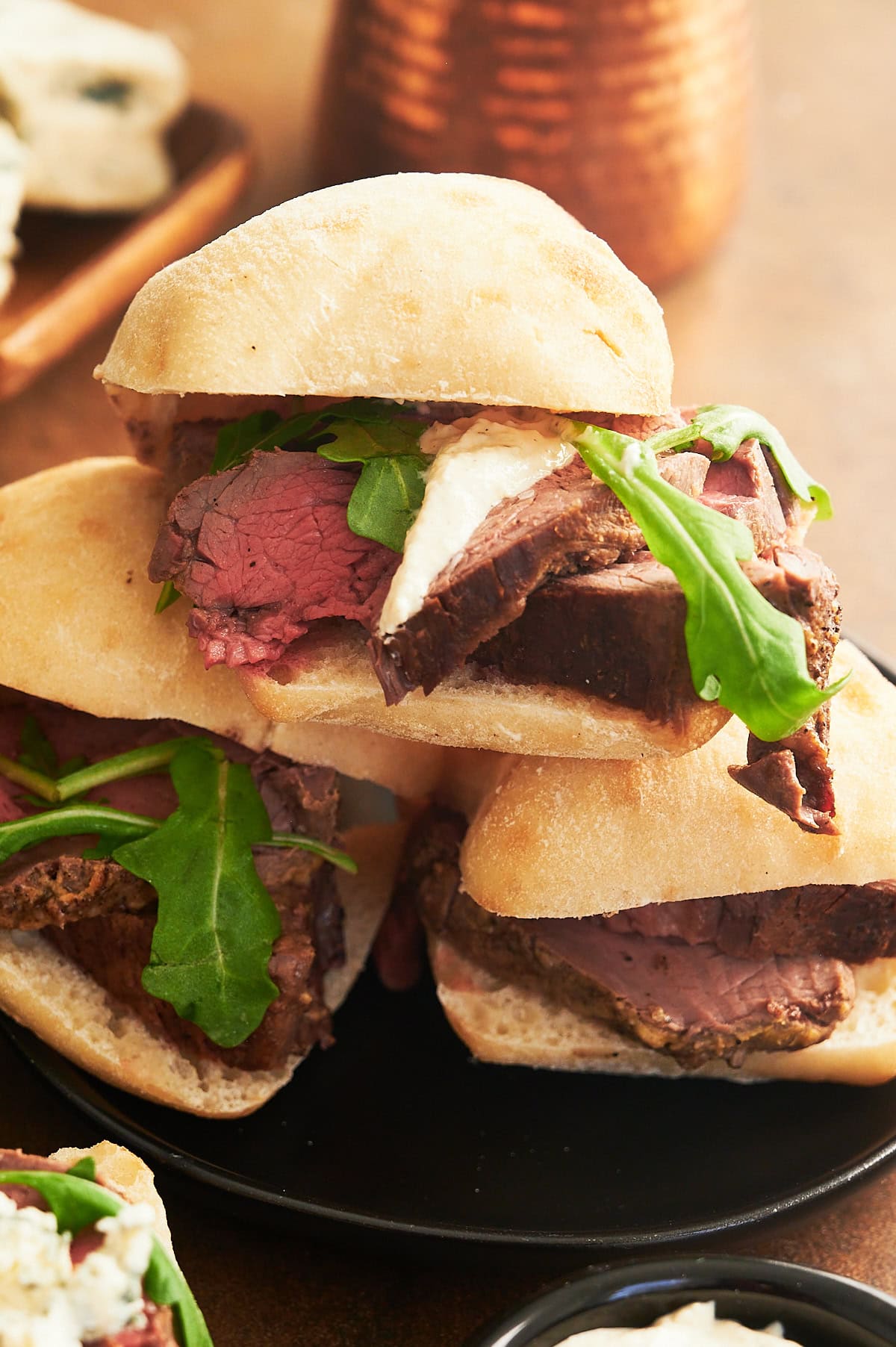 stack of beef tenderloin sliders on black plate.