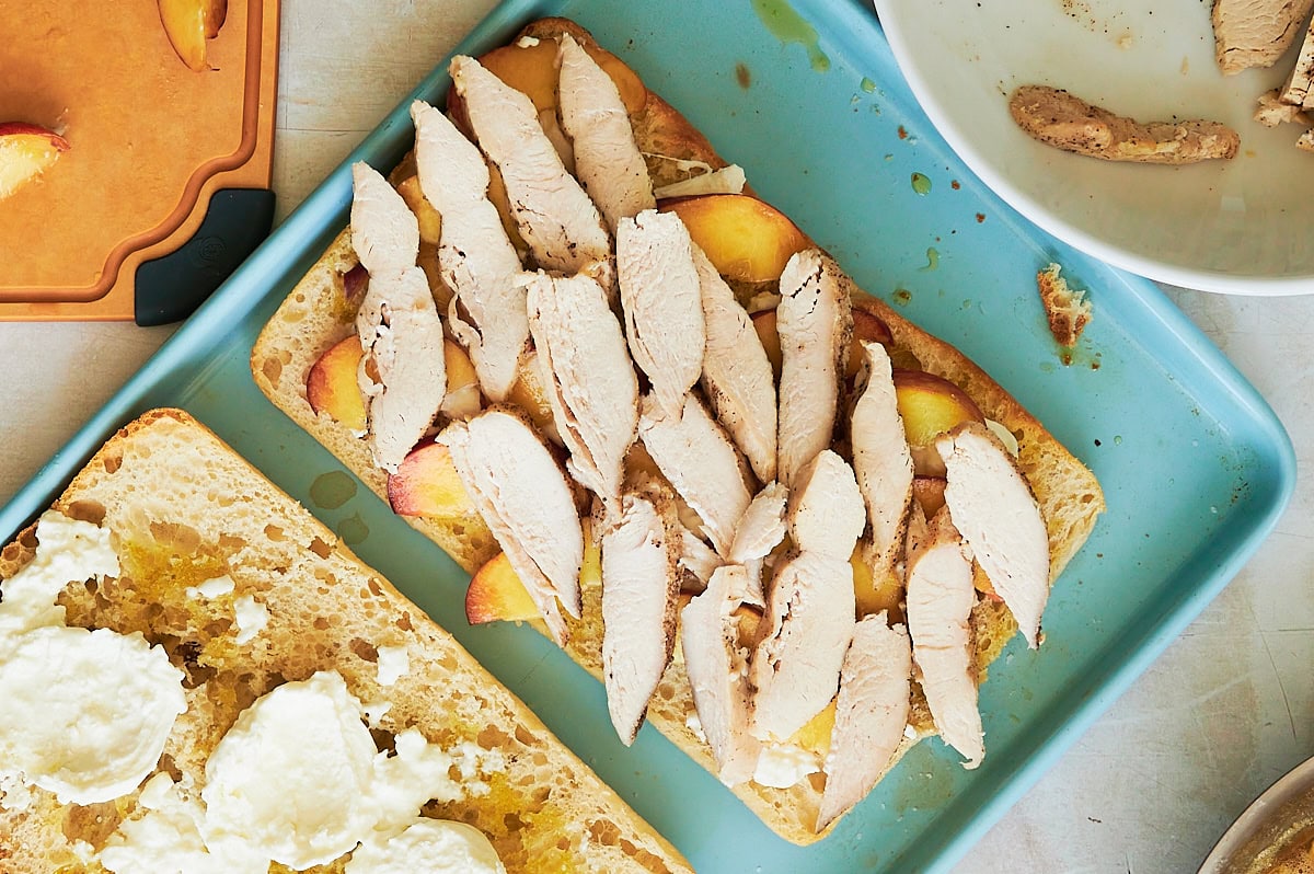 large ciabatta bread layered with peaches and chicken.