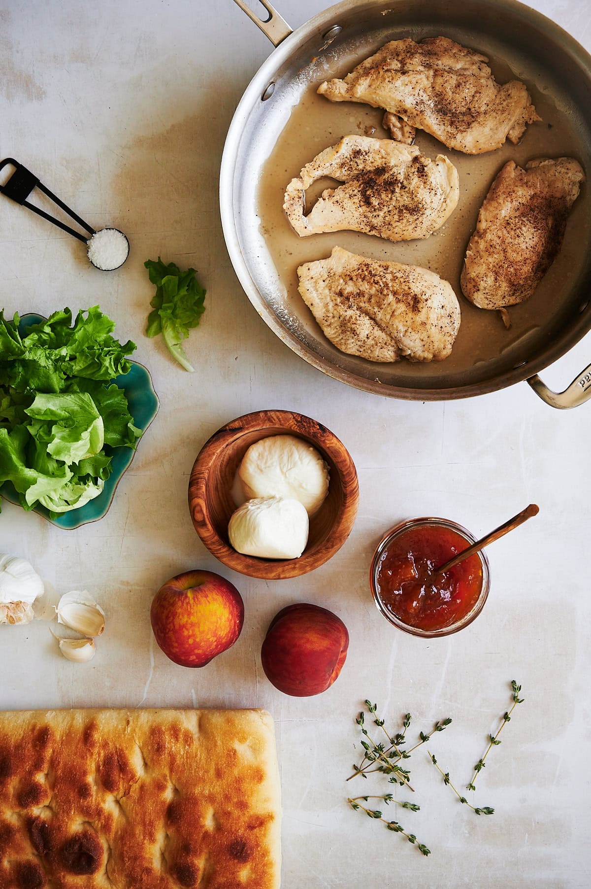 Ingredients for peach burrata chicken sandwich on white background.