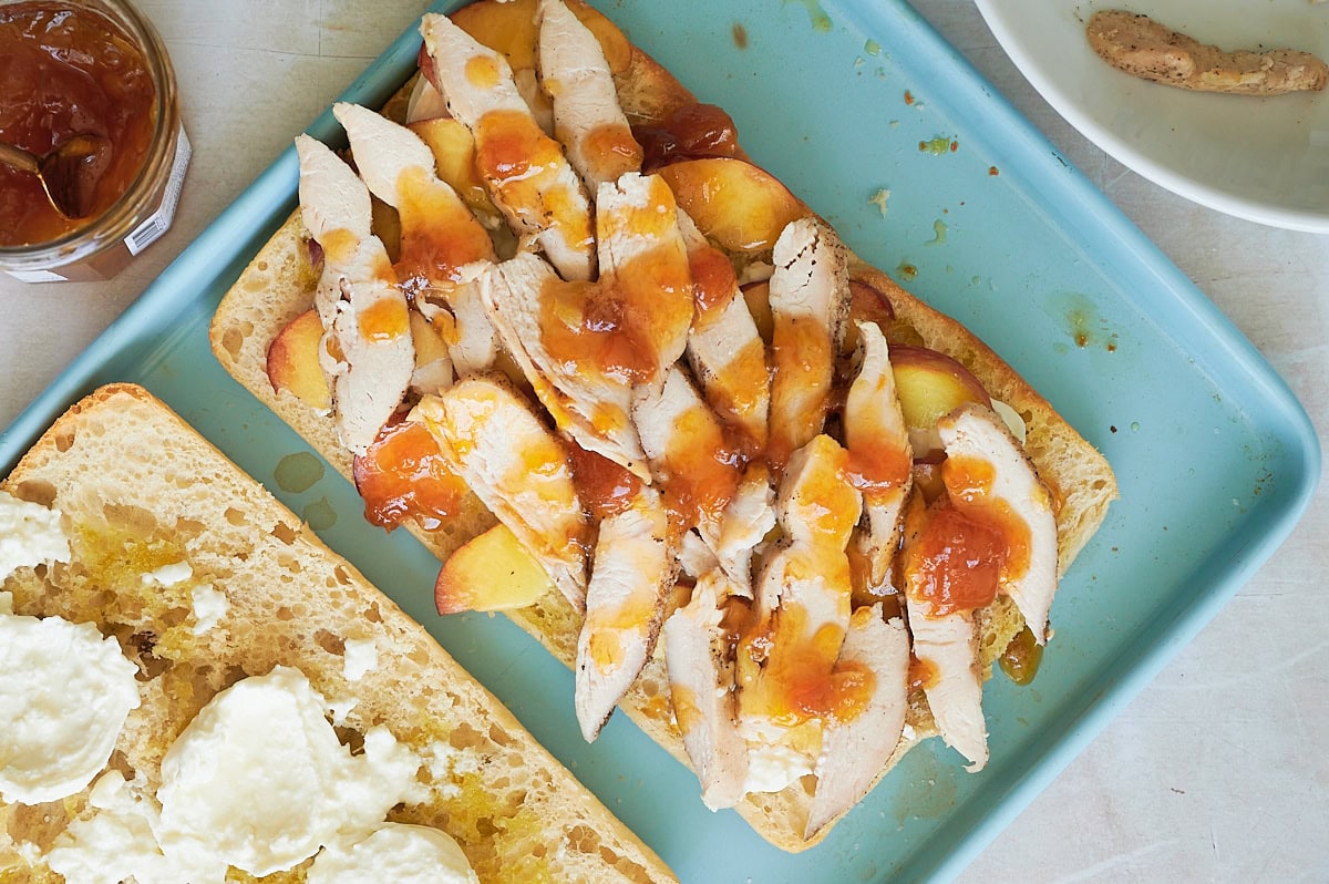 large ciabatta bread layered with peaches, chicken and drizzled with peach spread.