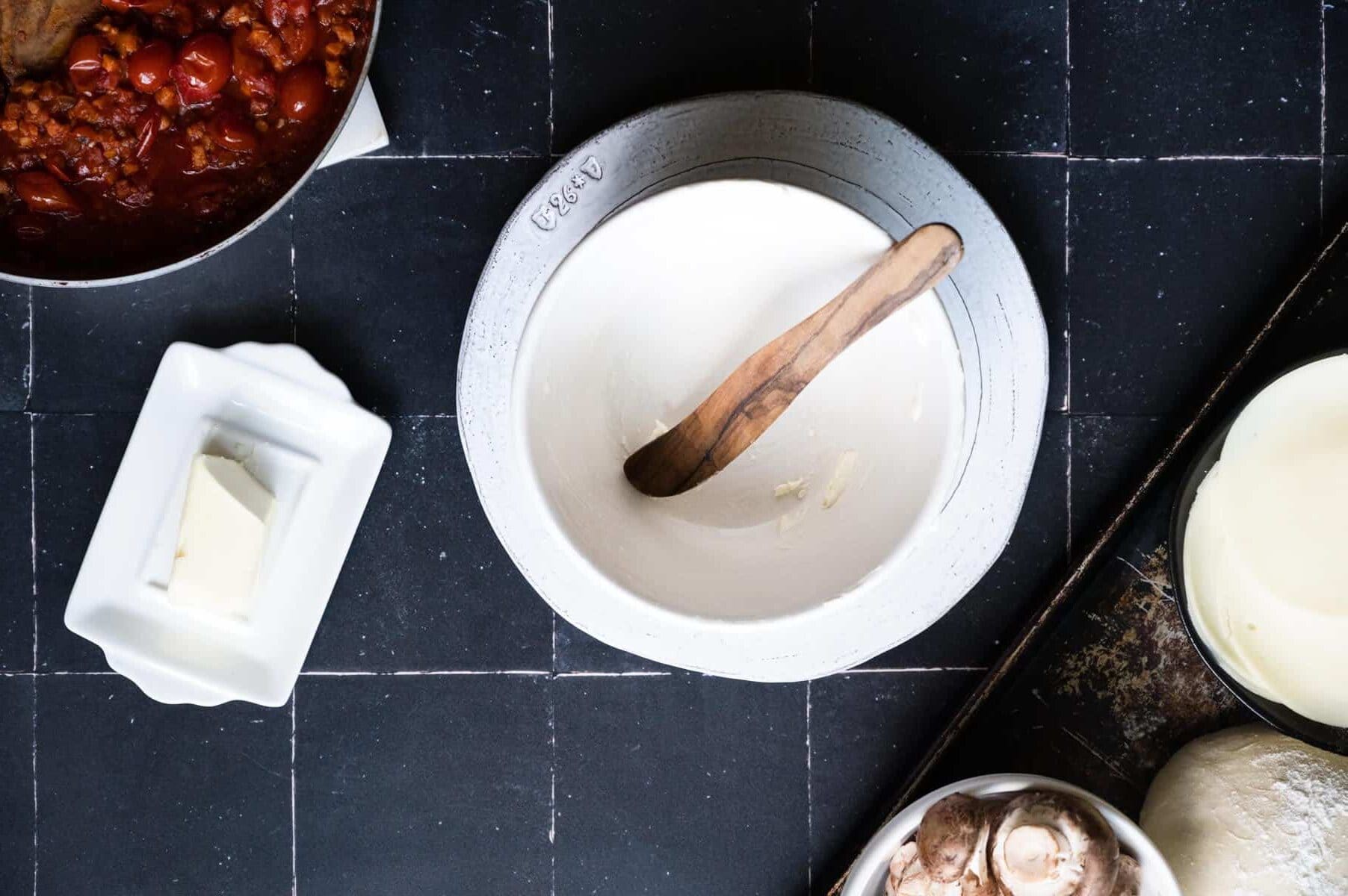 white bowl smeared with butter and a wooden spreader.