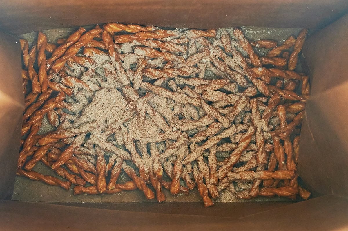 butter braid pretzels topped with cinnamon sugar mixture at the bottom of a brown paper bag.