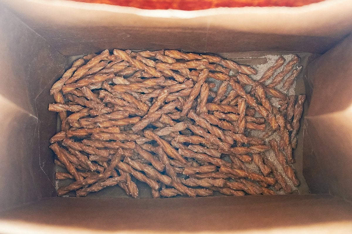 mixed cinnamon sugar pretzels at the bottom of a brown paper bag.