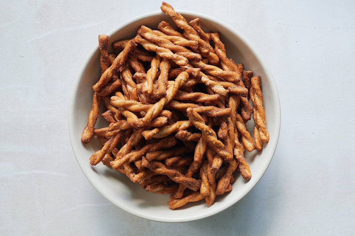 white bowl of cinnamon pretzels on a white background.