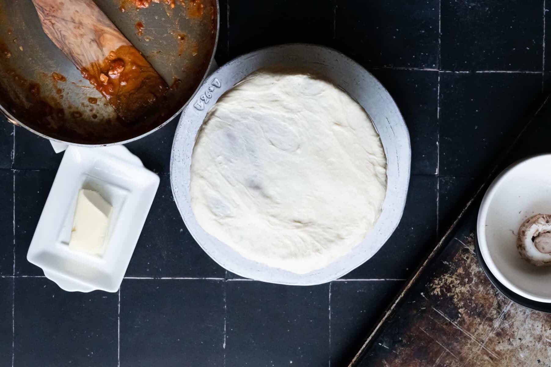 pizza dough stretched over a bowl sitting on a white plate.