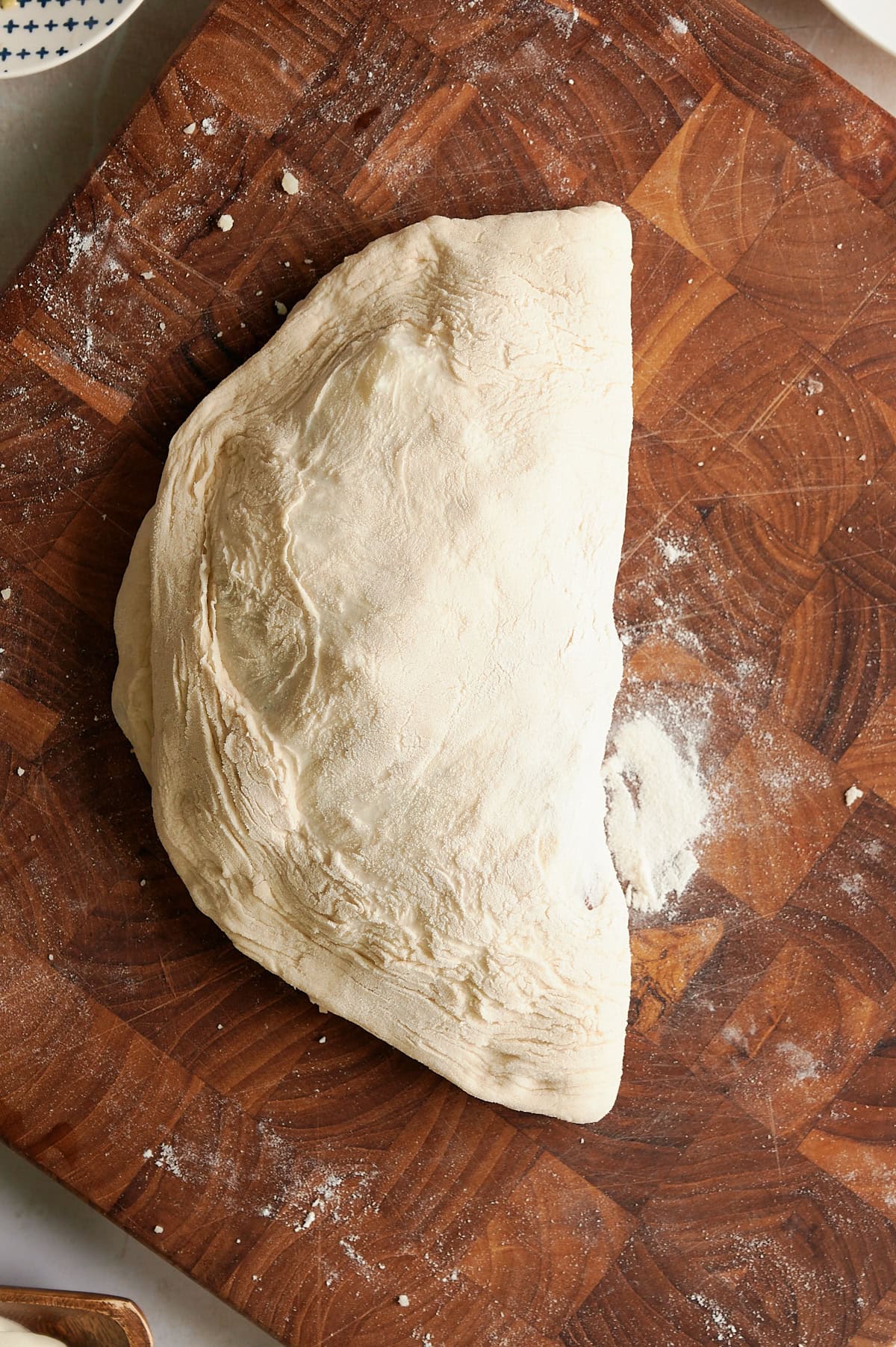 unbaked, closed beef calzone on floured, wooden cutting board.