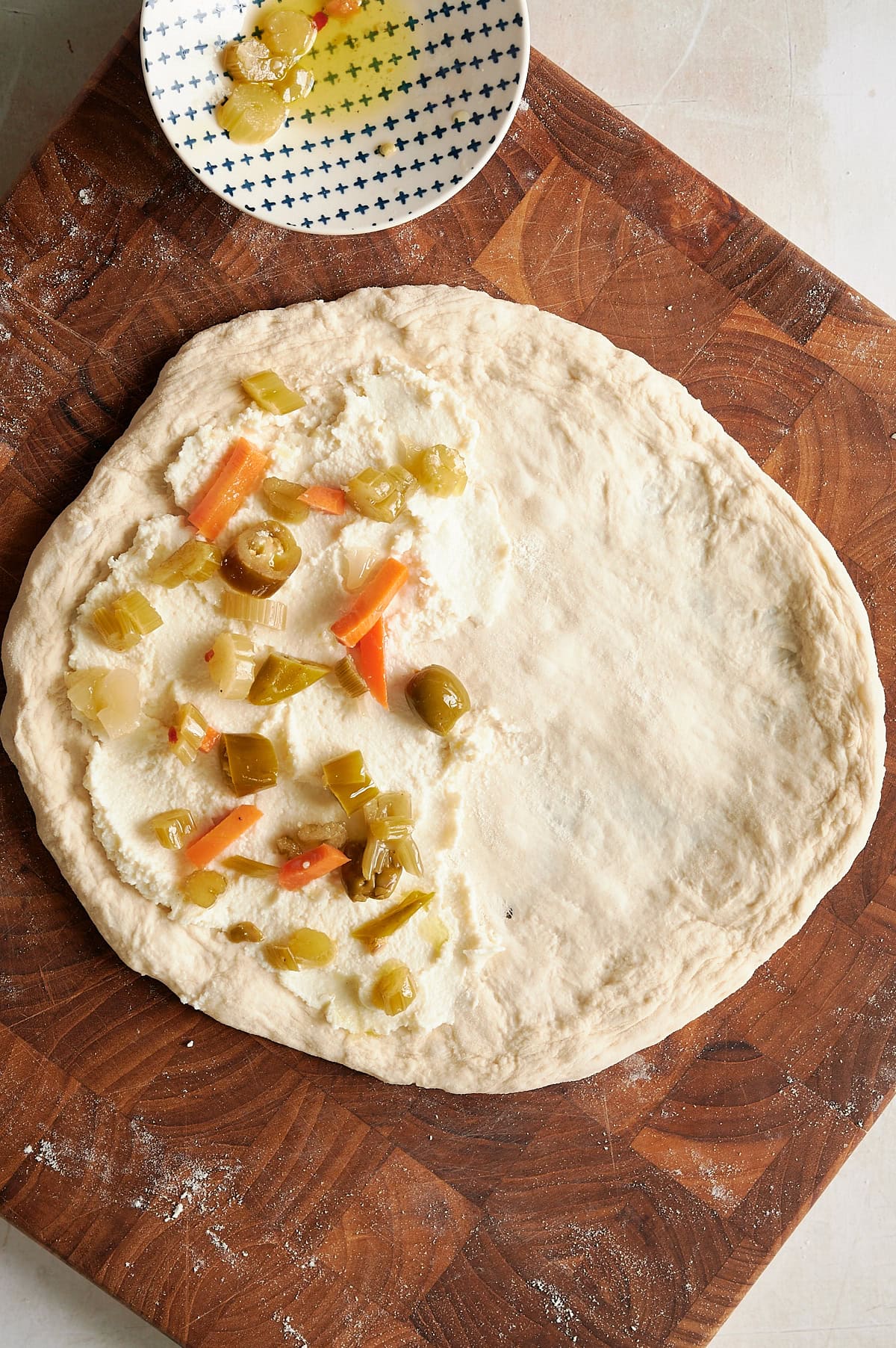 ricotta on left side of calzone dough sprinkled with giardiniera.