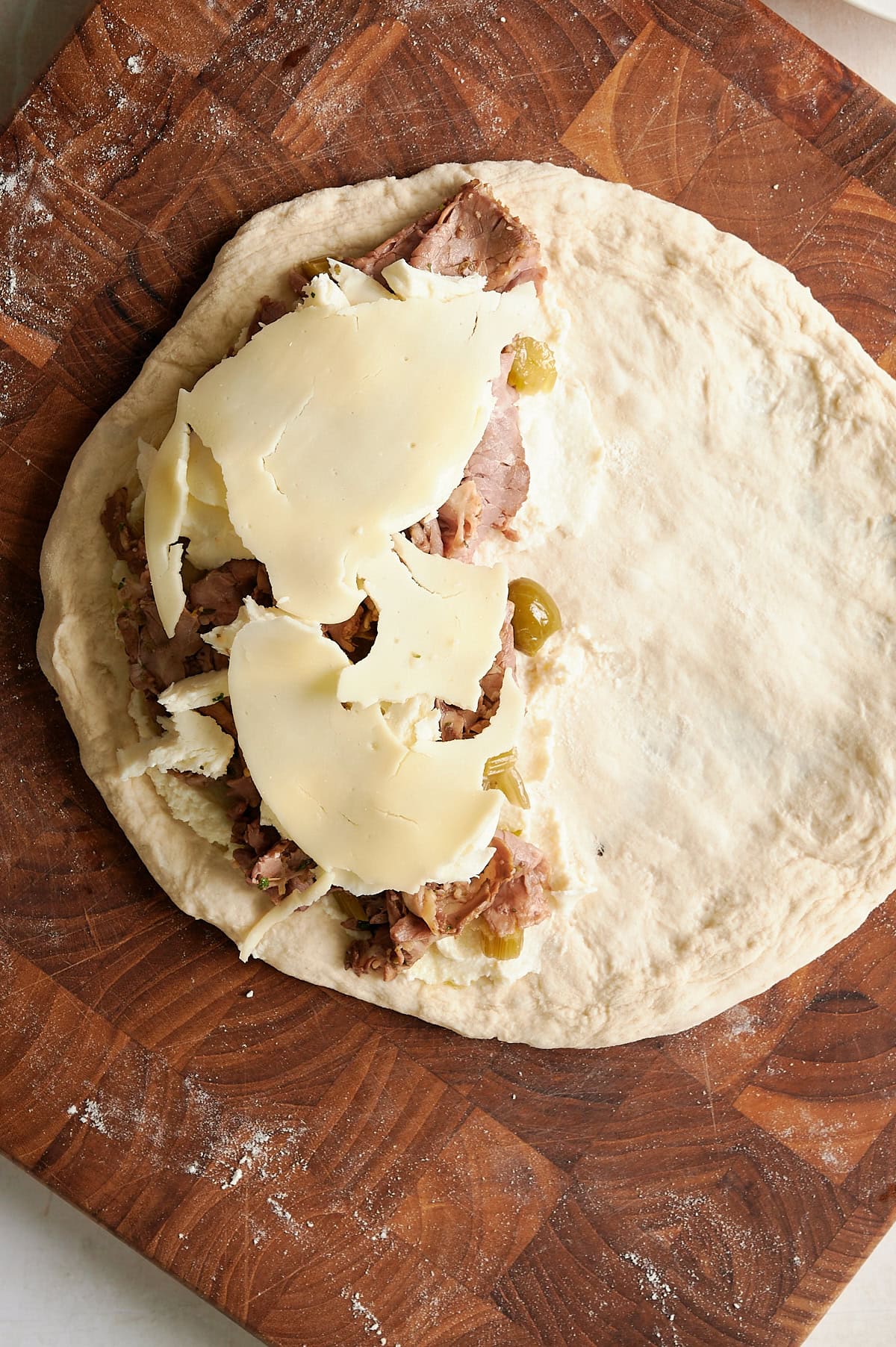 open faced beef calzone topped with provolone slices.