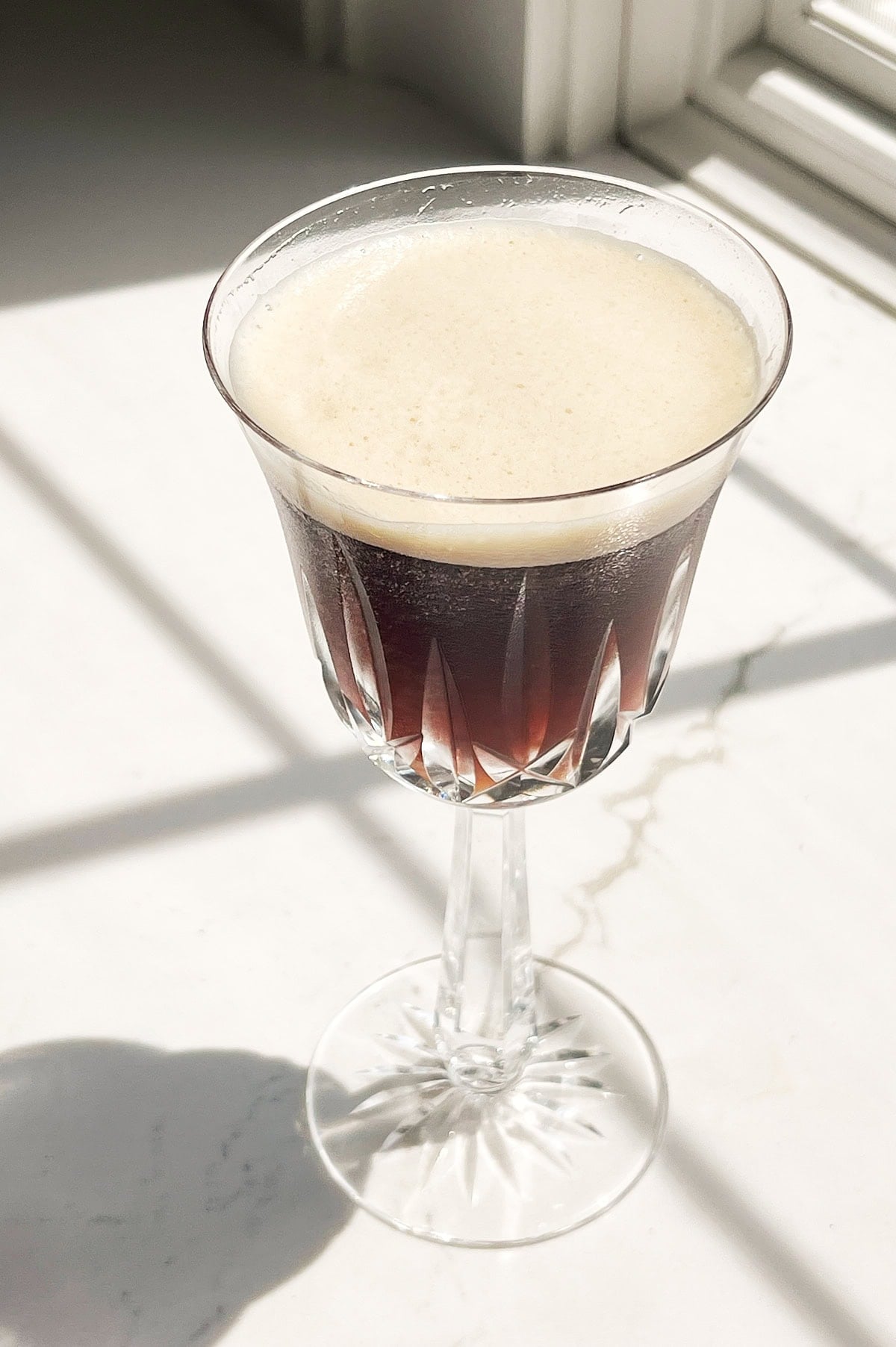 Wine glass of Italian iced coffee on a white marble counter.