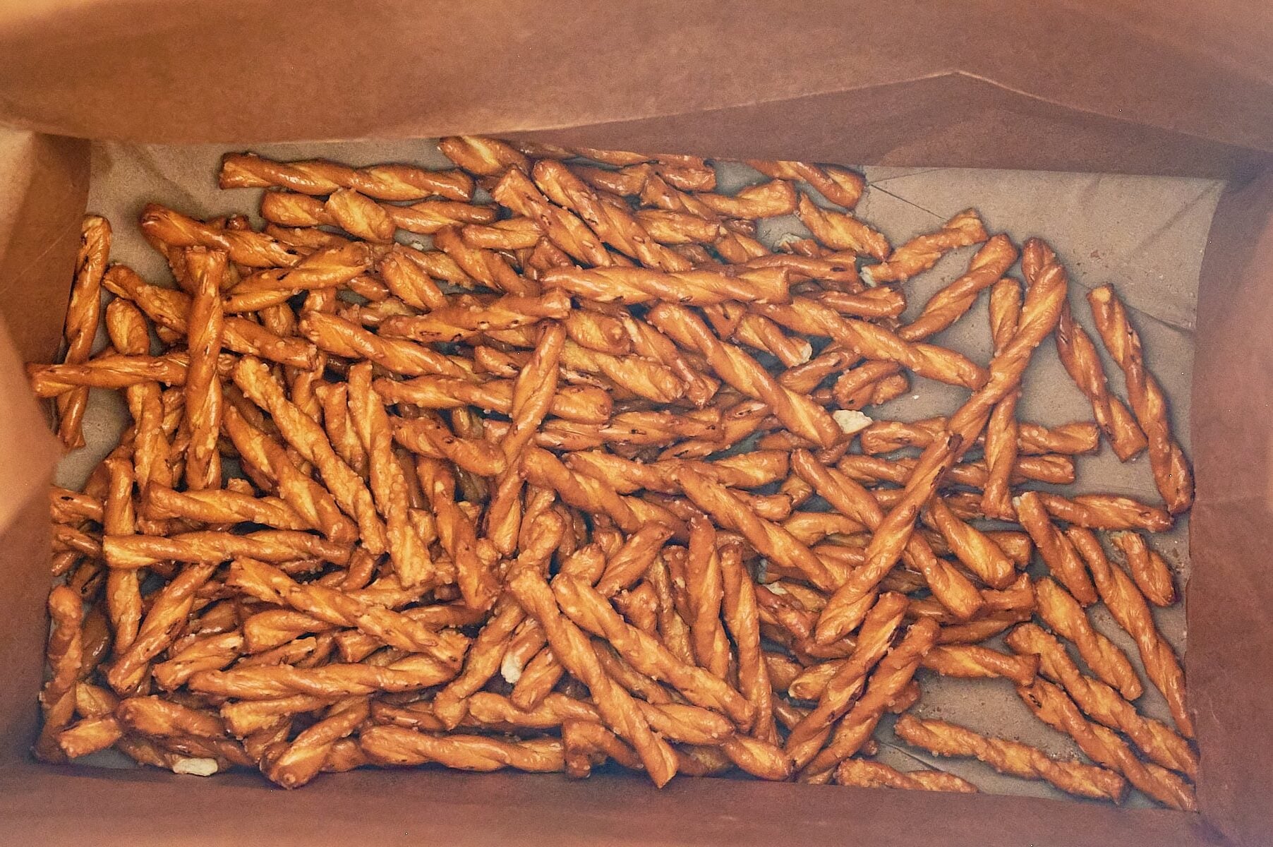 Butter braid pretzels at the bottom of a brown paper bag.