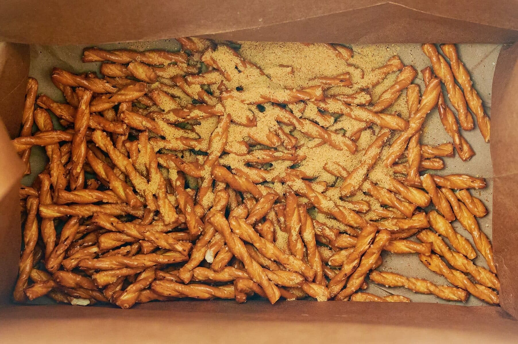 seasoning blend added to butter braid pretzels in bottom of brown bag.