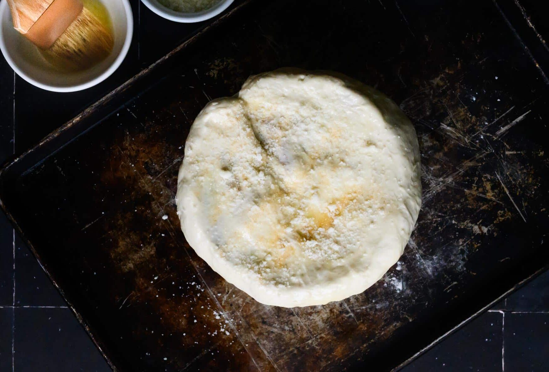 uncooked pizza dough sprinkled with cheese covering a bowl.