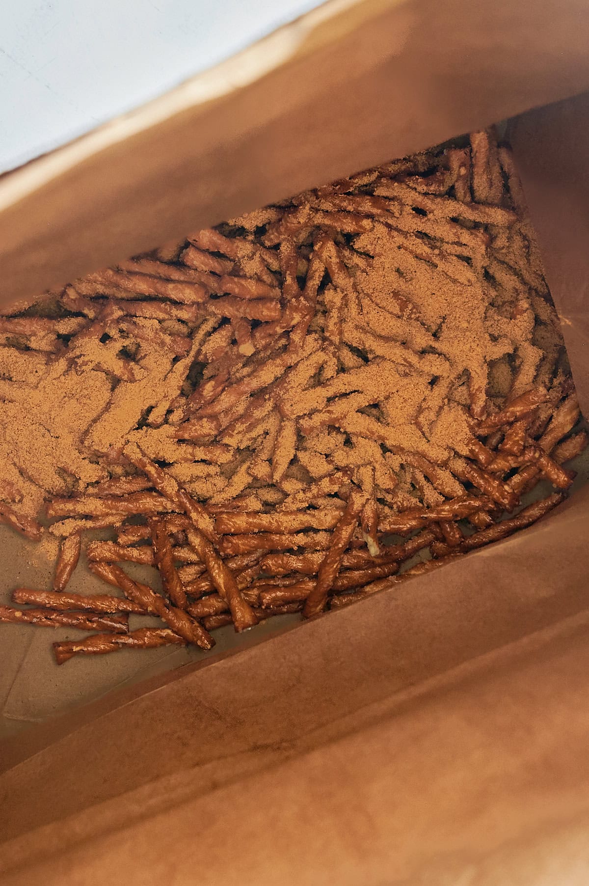 spicy seasoning on pretzels in brown paper bag.